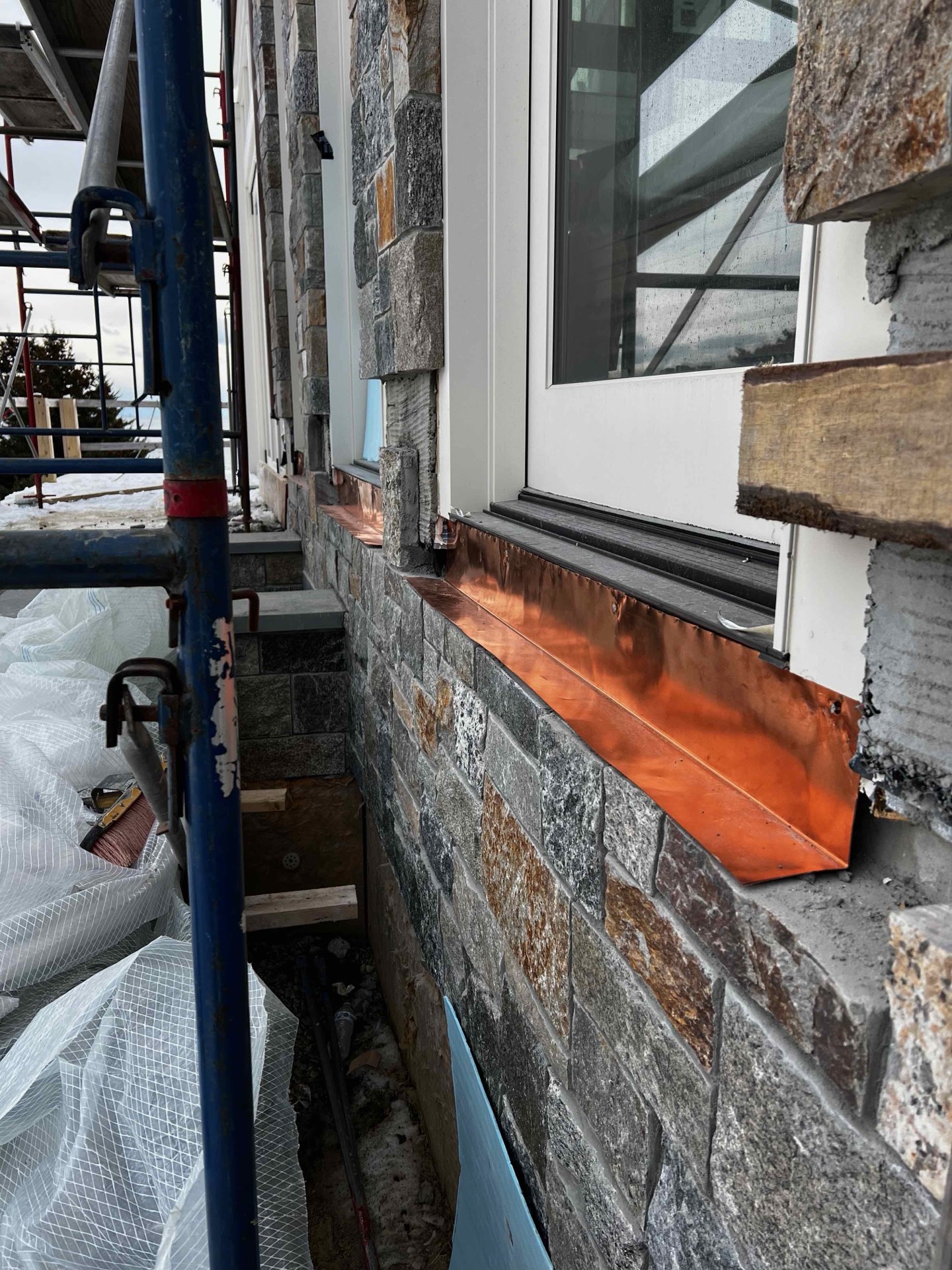 Copper flashing glowing against a granite veneer wall
